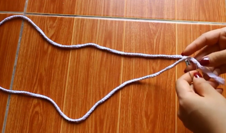 Bạn chuẩn bị một sợi dây dù dài và một chiếc kim rồi luồn chúng qua lỗ nhỏ đã để trống trước đó.